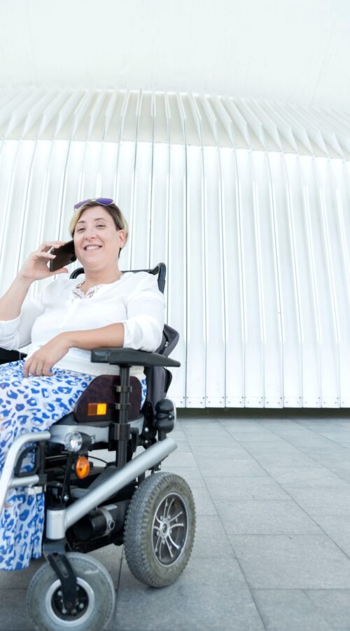 portrait of a smiling woman with disability in a wheelchair talking on a smartphone